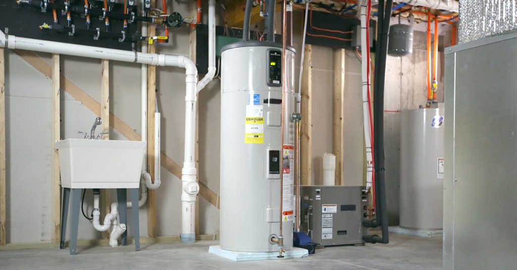Heat pump water heater and mechanical systems installed in a Maine basement utility room.