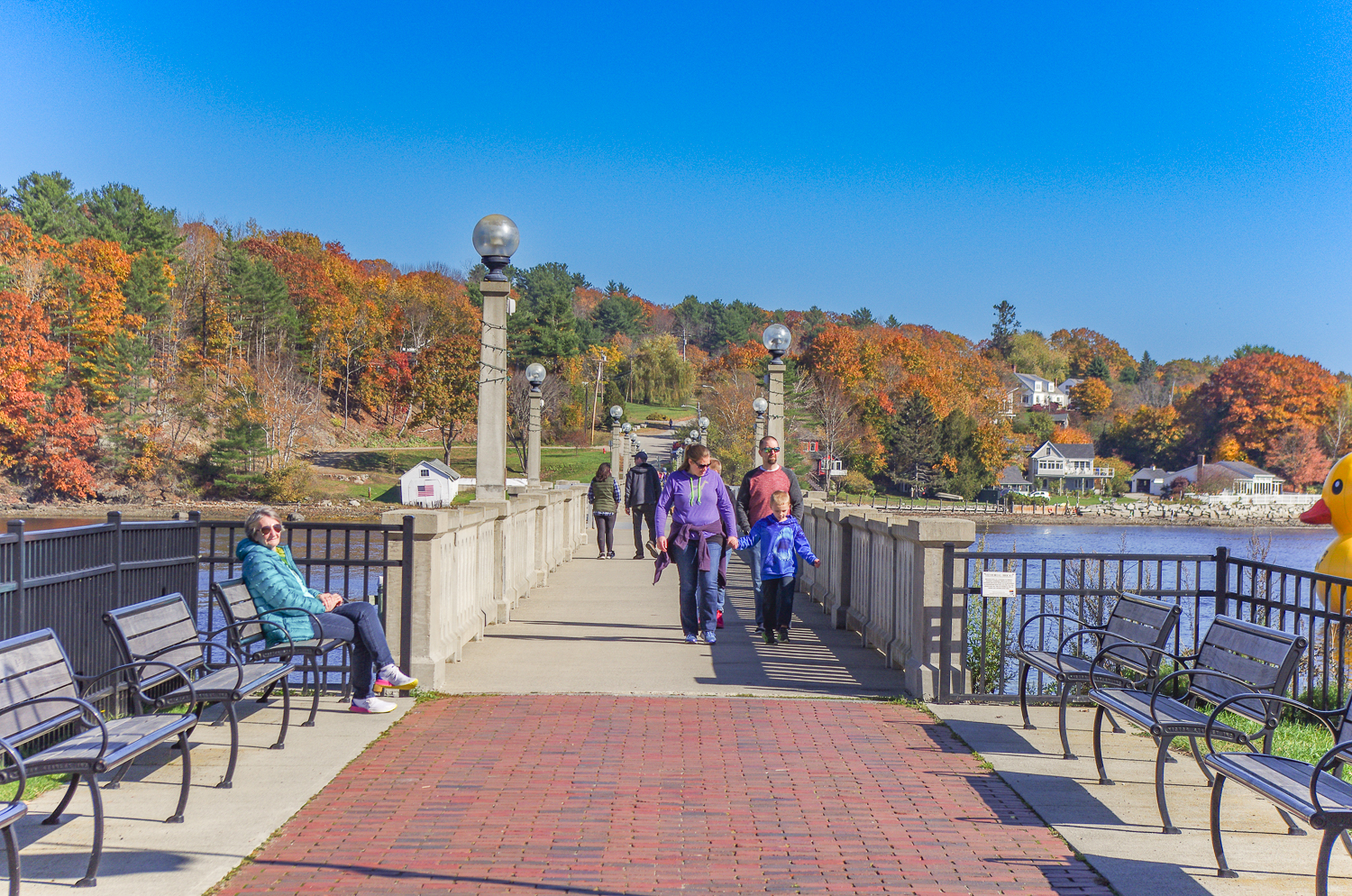 People walking along the harbor walk in downtown Belfast Maine during fall.