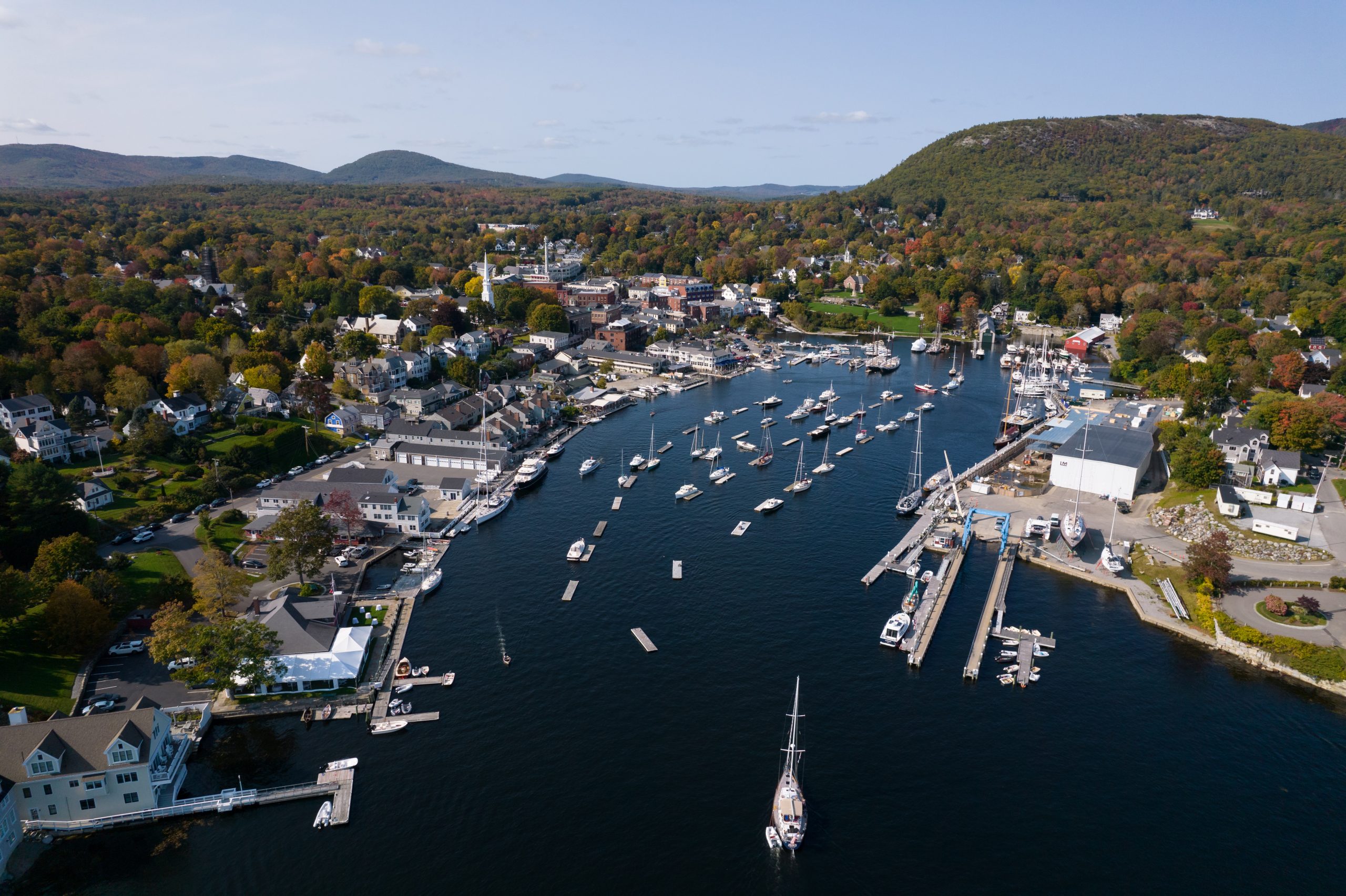 Camden Maine harbor with boats and fall foliage and mountains in the background