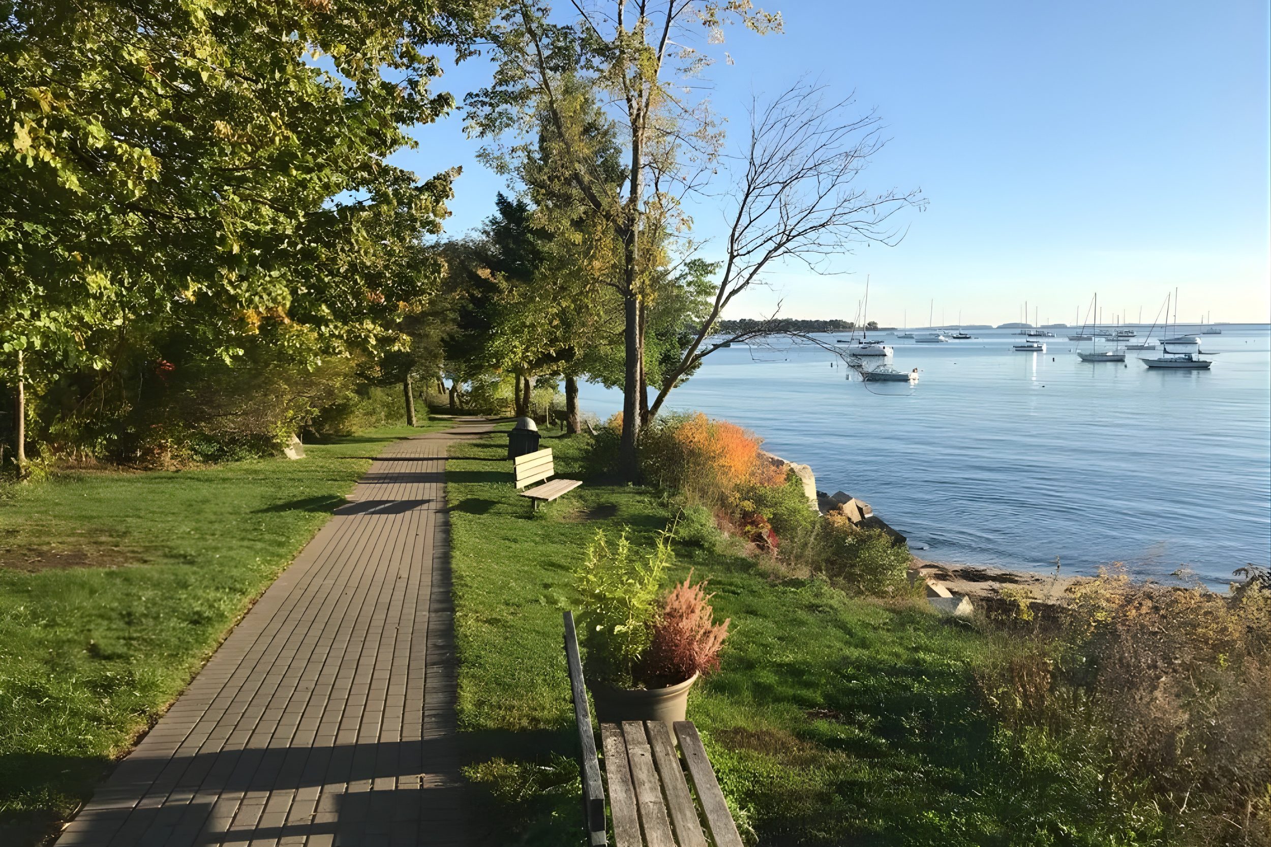 Rockland Harbor Trail in Maine with walkway, benches, trees, and ocean views