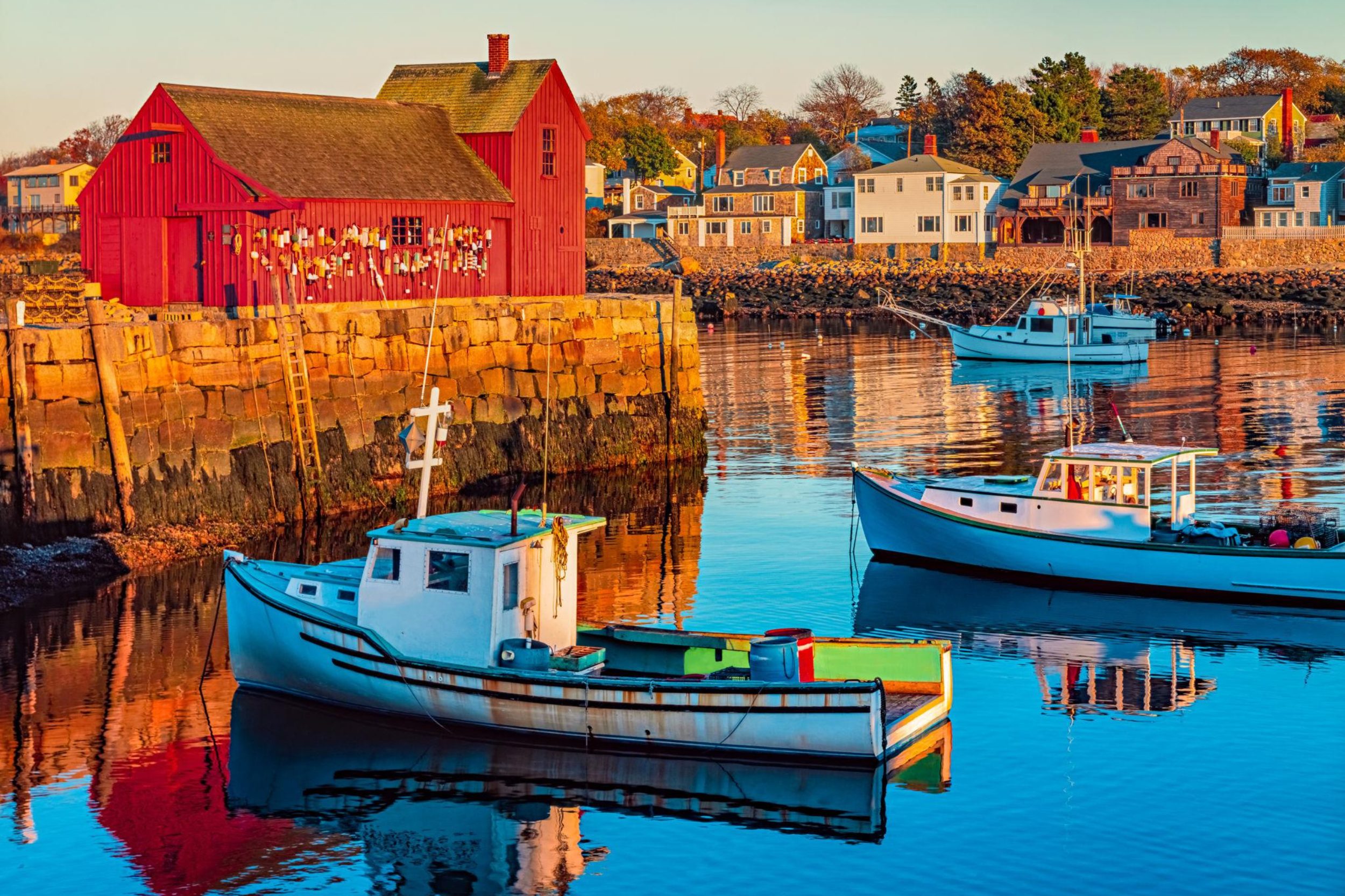 Rockport Harbor Maine with fishing boats and iconic red boathouse at sunset