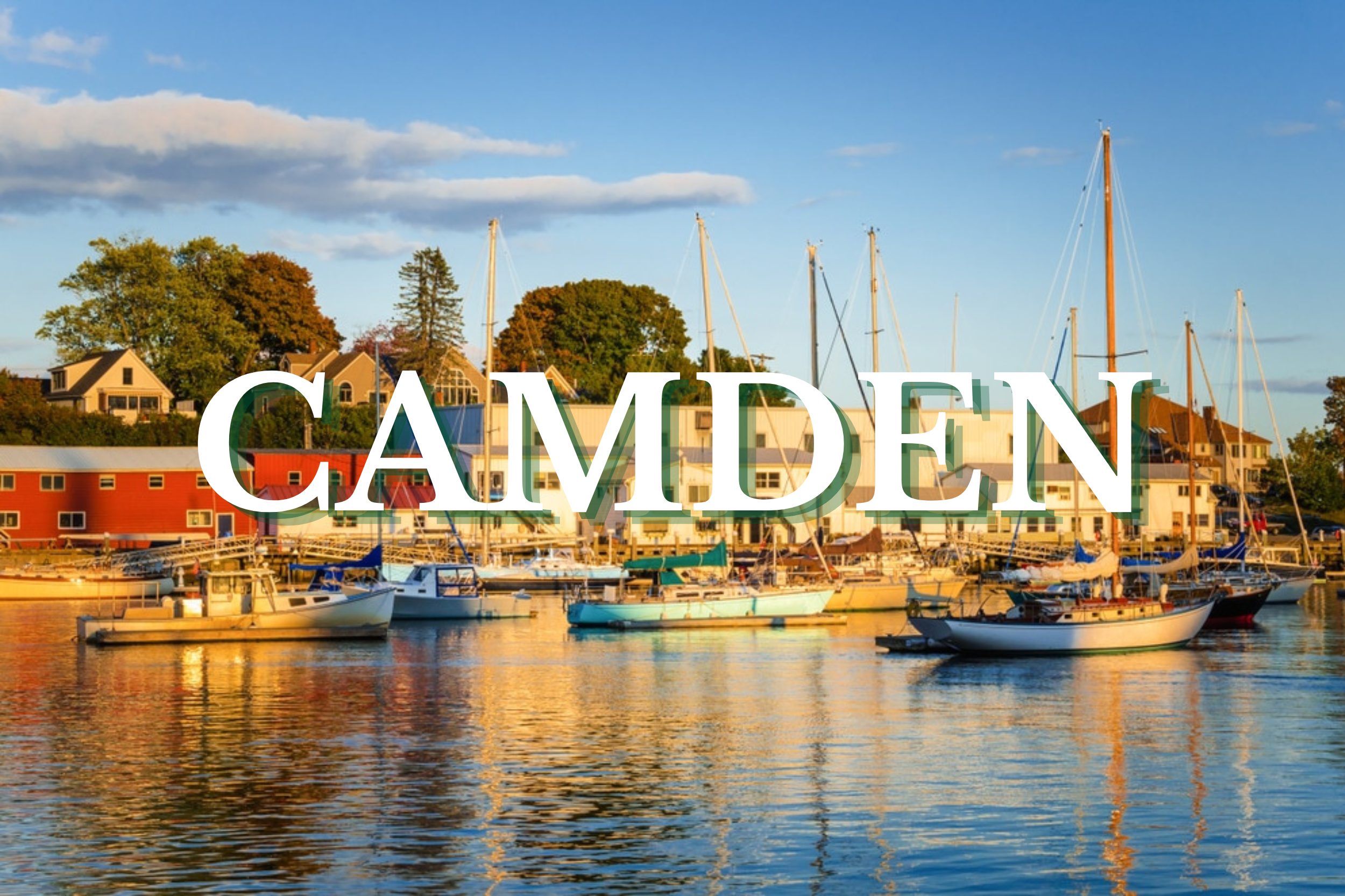 Sailboats docked in Camden Harbor during golden hour with waterfront buildings in Camden, Maine