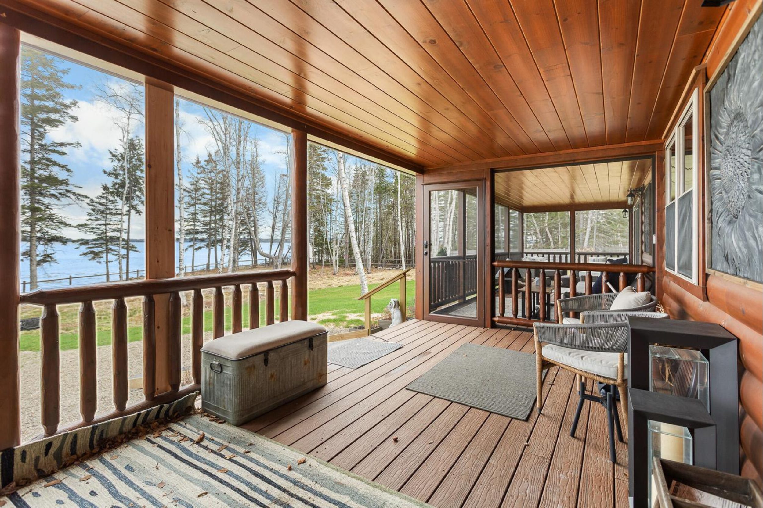 Covered porch seating area with waterfront views at log-style home in Islesboro, Maine