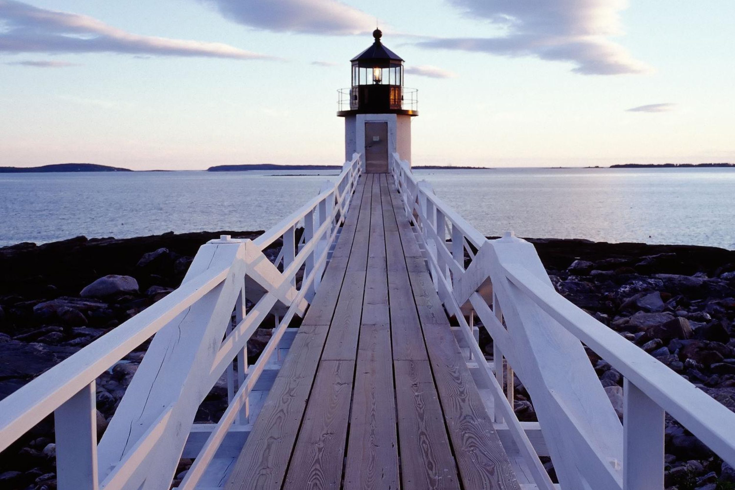 Marshall Point Lighthouse in Port Clyde Maine with wooden walkway over rocky coast