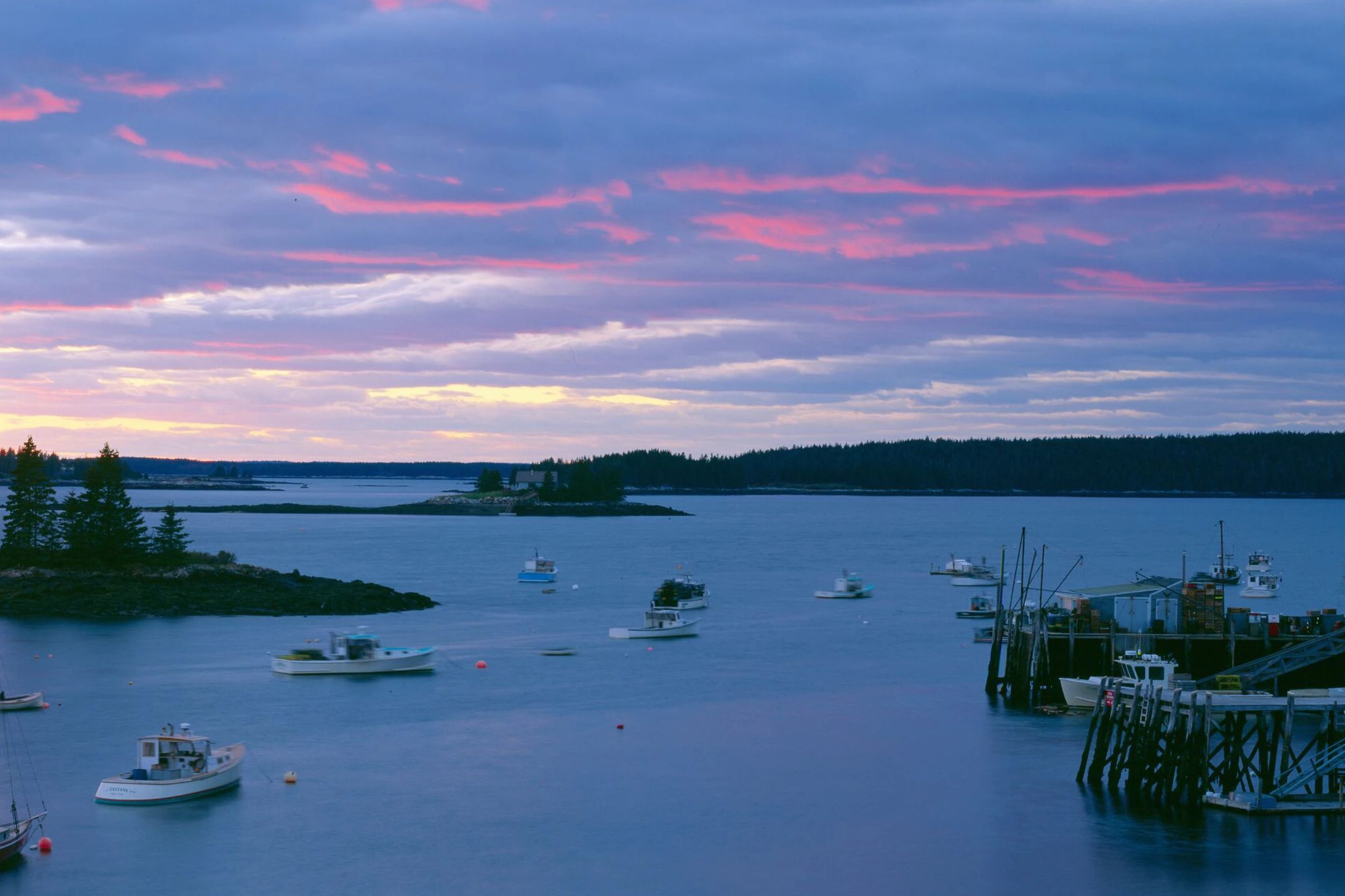Sunset over Port Clyde Harbor in St. George Maine with fishing boats and coastal islands