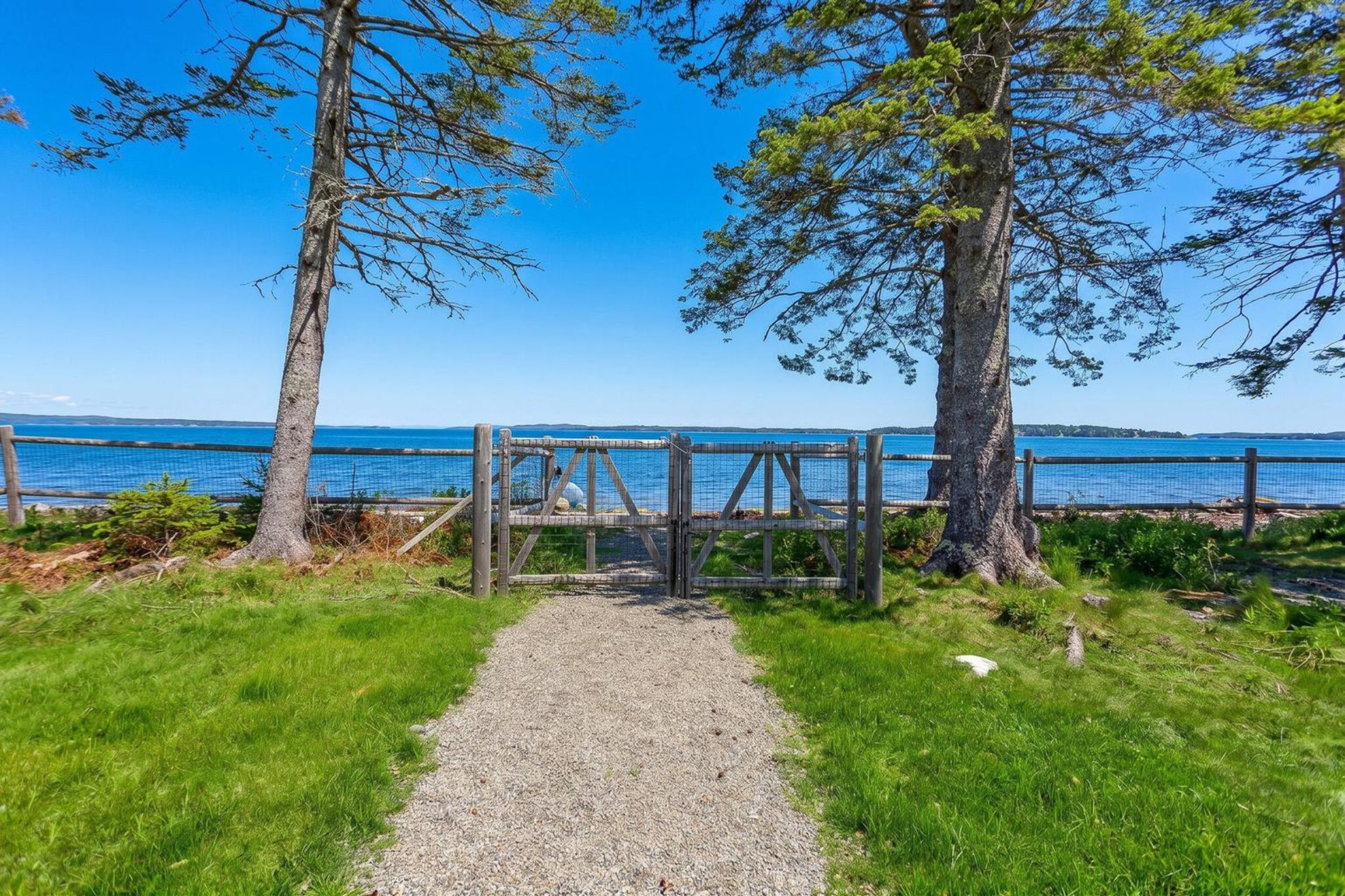 Gravel path leading to gated waterfront access with ocean views in Islesboro, Maine