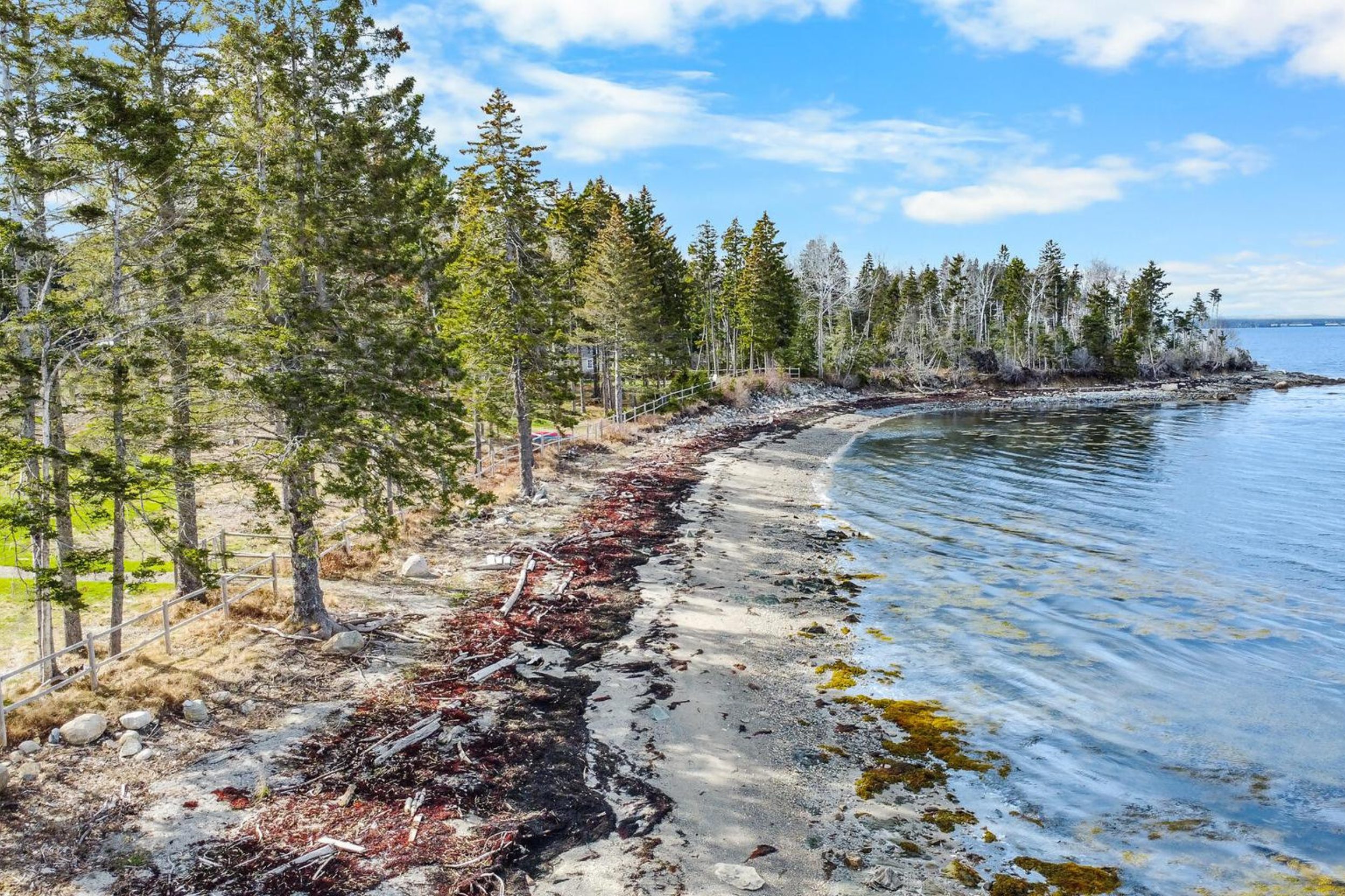 Aerial view of private shoreline and sandy beach along a wooded waterfront property in Islesboro, Maine