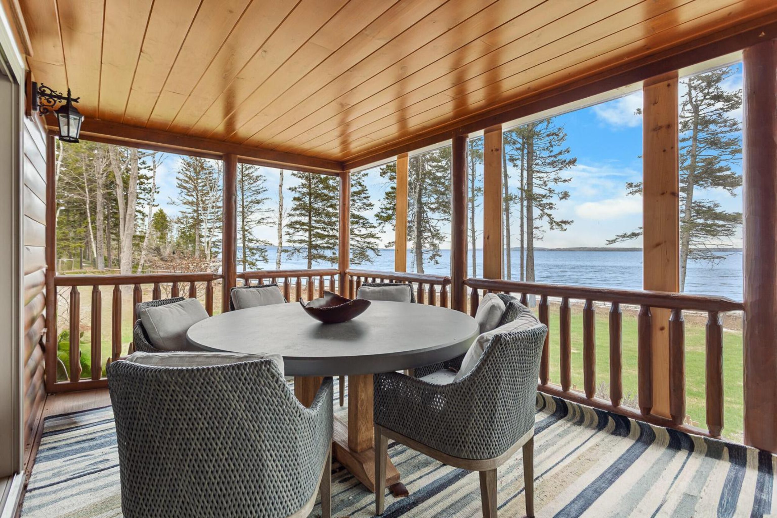 Screened porch with dining table and panoramic water views at waterfront home in Islesboro, Maine