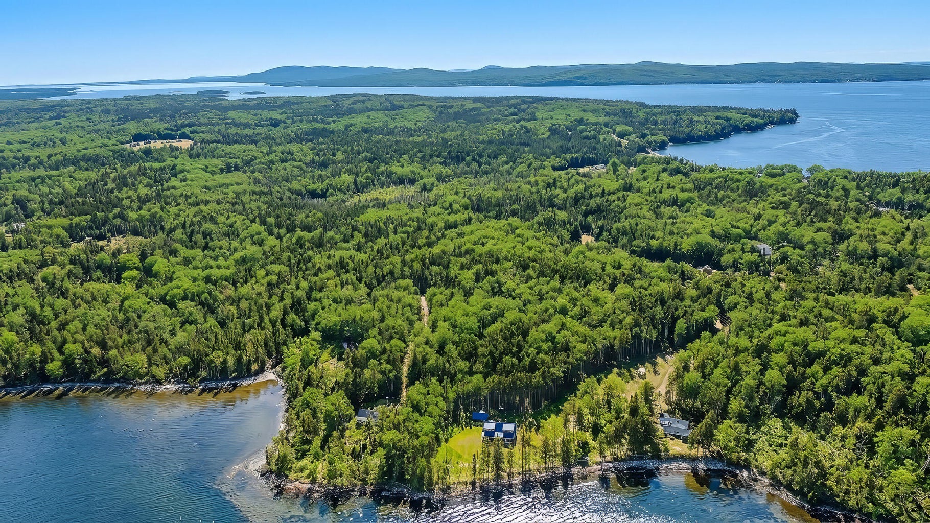 Aerial view of a forested waterfront property overlooking a large bay and surrounding Maine coastline