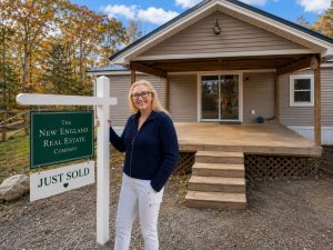 Lisa Decker Griffith standing beside a "Just Sold" real estate sign in front of a recently sold home in Maine