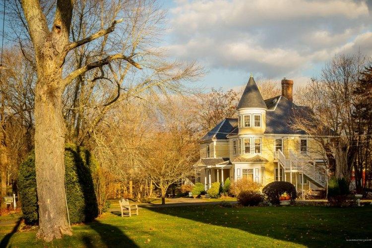 Historic Victorian home with a turret, large front lawn, and mature trees in Midcoast Maine